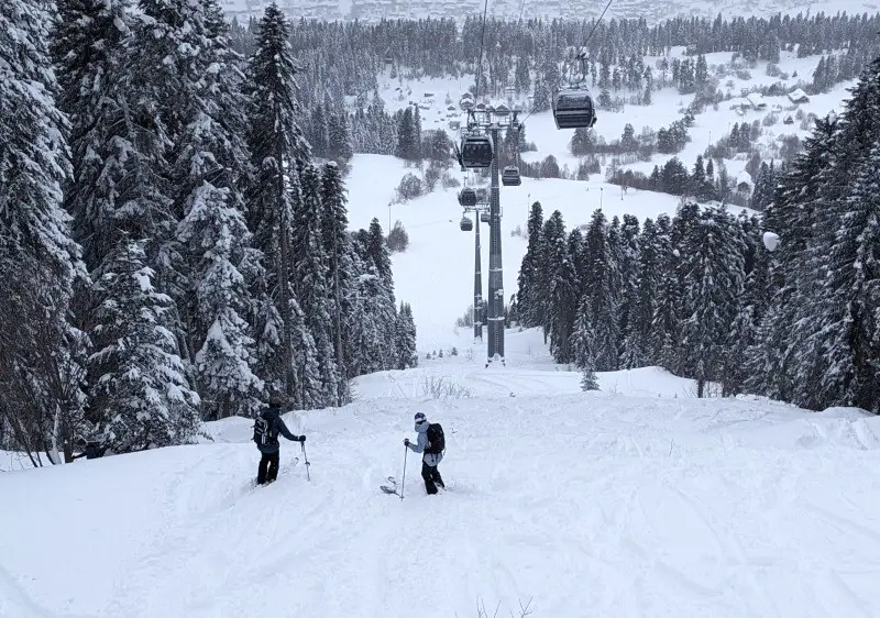 Winter scene at Hatsvali – Mestia in Ieli, Georgia featuring an active ski resort with a skier on the slope, and a ski lift ascending to the peak.