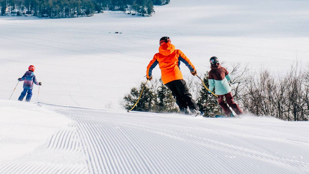 Pleasant Mountain in USA - two people skiing down a snow covered slope.