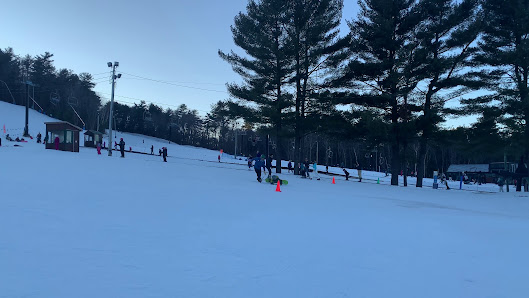 Winter sports enthusiasts enjoying a day of skiing at Pleasant Mountain in Bridgton, Maine. Groups of skiers dash down the snow-covered slopes amidst a picturesque winter scene.