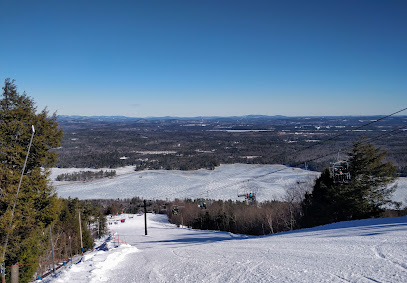A winter sports scene at Pleasant Mountain Maine showcasing a ski resort with a ski lift where a skier gracefully glides down the mountain.
