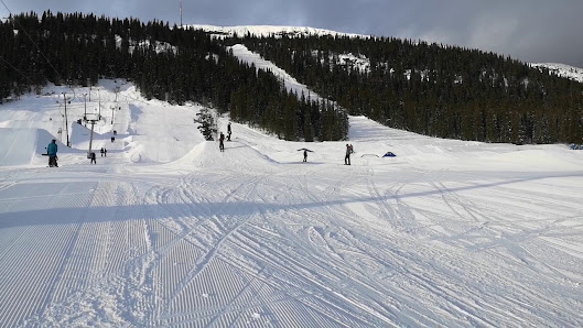 A skier descends down the slopes at Funäsdalsberget ski resort in Funäsdalen Northern Sweden with a ski lift and snowmobile visible in the picturesque winter sports scene.