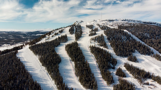 Ski resort in Funäsdalen, Northern Sweden with skiers enjoying the snow-covered slopes. A ski lift aids in transportation up the Funäsdalsberget mountain. A quintessential winter sports scene.