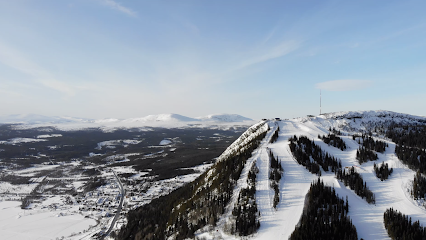 A winter scene in Funäsdalen Sweden featuring a bustling ski resort amidst a stunning fjord landscape with a ski lift marking the approaching mountain's slope.