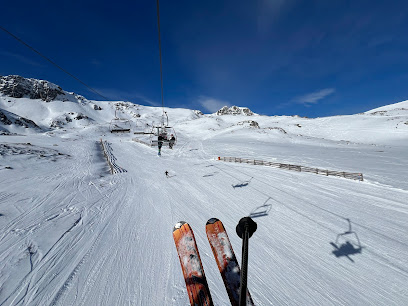 A winter sports scene at San Isidro-Zona Cebolledo Spain with a ski resort a challet a skier on the slopes and a ski lift in view.