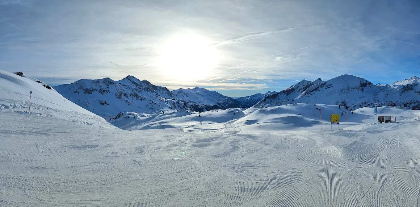 A vibrant winter sports scene at Obertauern in Austria with a skier gliding down the slope. The background presents a quaint chalet, part of the popular ski resort.