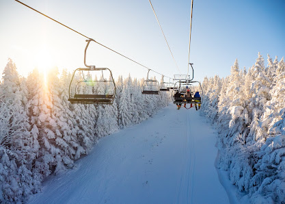 A scenic winter view at Massif du Sud Quebec featuring a ski lift surrounded by snow covered slopes bustling with winter sports activities.