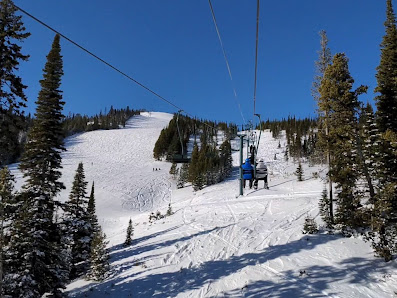 A skier is riding a ski lift at the Showdown Ski Resort in Neihart Montana USA highlighting a bustling winter sports scene with a hint of a family skiing together.