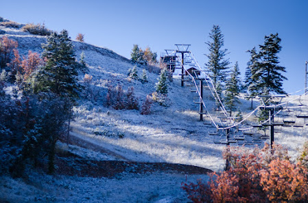 A ski lift is ascending Cherry Peak's snow-covered incline at a ski resort in Richmond Utah. The beautiful winter scene is punctuated by the excitement of winter sports activities.