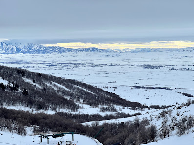 View of Cherry Peak ski resort in Richmond Utah showcasing a vibrant winter sports scene. Ski lift ascending across the snow-covered slopes contributing to stunning winter scenery.