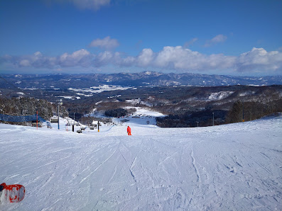 A skier glides down the slopes of Chokai Kogen Yashima ski resort in Tōhoku, Japan. The stunning winter scenery is dotted with chalets amidst the pristine snow.