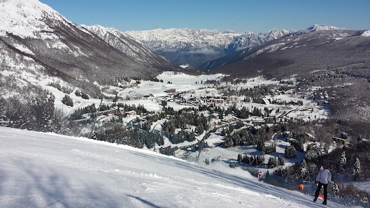 A picture of a chalet at Piancavallo ski resort in Italy featuring snow-covered slopes being enjoyed by winter sports enthusiasts.