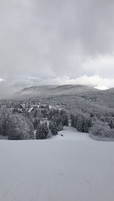 A chilling scenic view of Piancavallo in Italy featuring a charming chalet amidst a bustling ski resort surrounded by remarkable winter scenery and majestic mountains.
