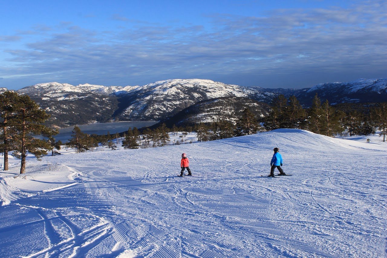 Vrådal Panorama in Norway - two people are skiing down a snowy hill.