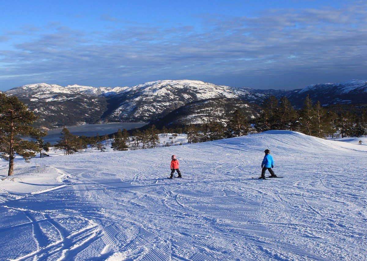 Vrådal Panorama in Norway - two people skiing down a snowy slope in the mountains.