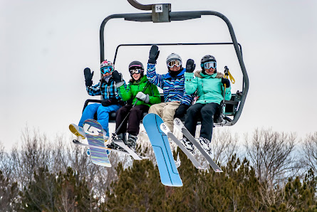 A ski lift ascends Cascade Mountain in Portage Wisconsin carrying a group of people in a delightful winter sports scene at a ski resort.