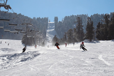 Winter sports enthusiasts engaging in skiing at the Red River ski resort in New Mexico USA. They're descending on clean white slopes under a ski lift.