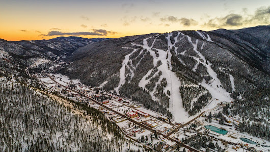 A captivating winter scene at Red River ski resort in New Mexico showcasing snow-covered slopes and a ski lift bustling with winter sports activities.