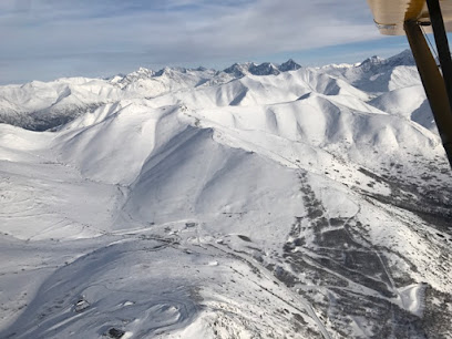 An image displaying a charming challet nestled in Arctic Valley Anchorage Alaska. The challet overlooks a bustling ski resort set against a majestic snow-covered mountain backdrop.