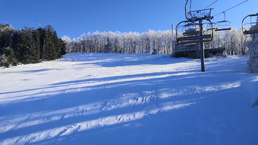 Ski resort at Snowparadise Veľká Rača Oščadnica in Slovakia featuring a busy winter sports scene, a ski lift, and a skier against the backdrop of stunning winter scenery.