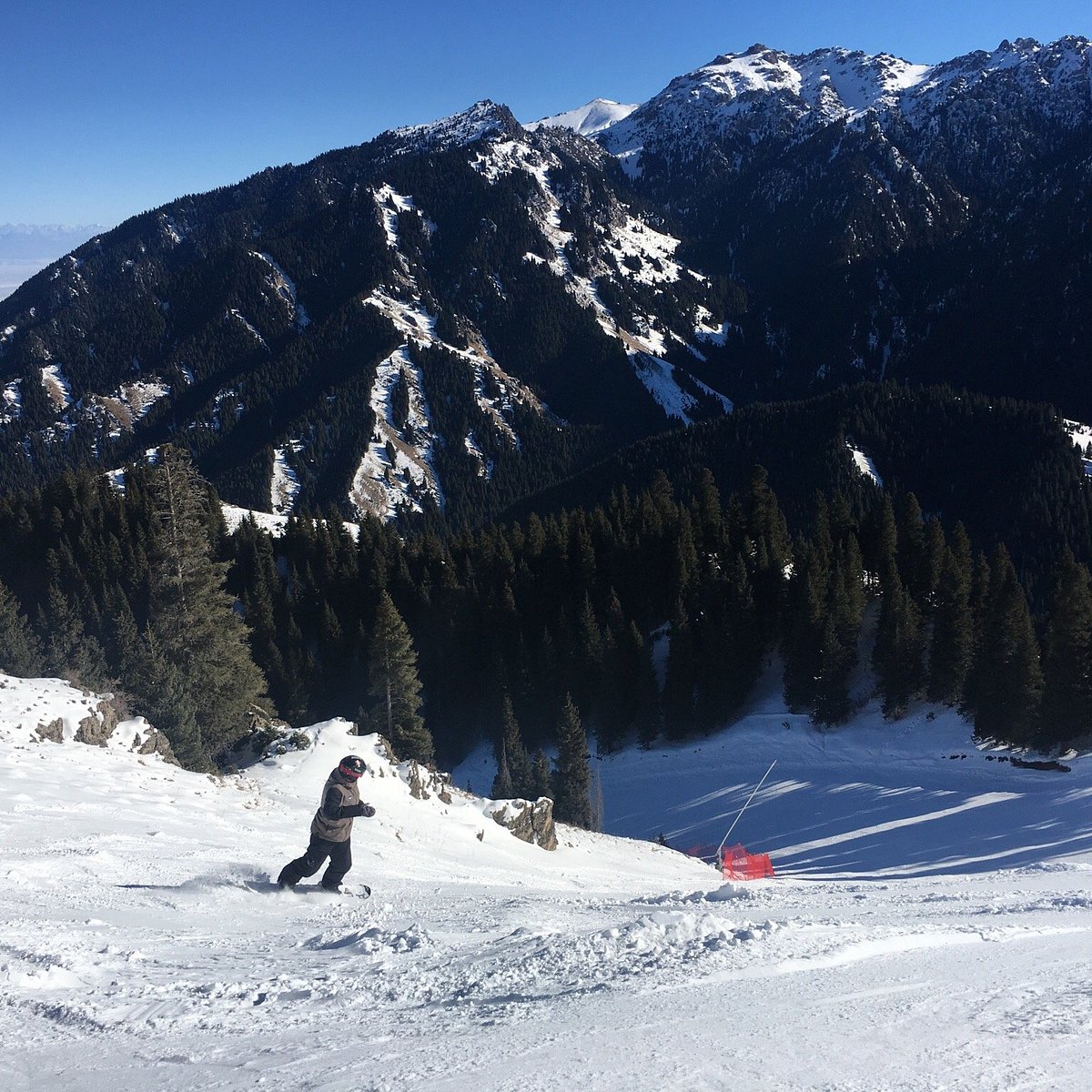 SilkRoad Ski in China - a person skiing down a snowy slope in the mountains.