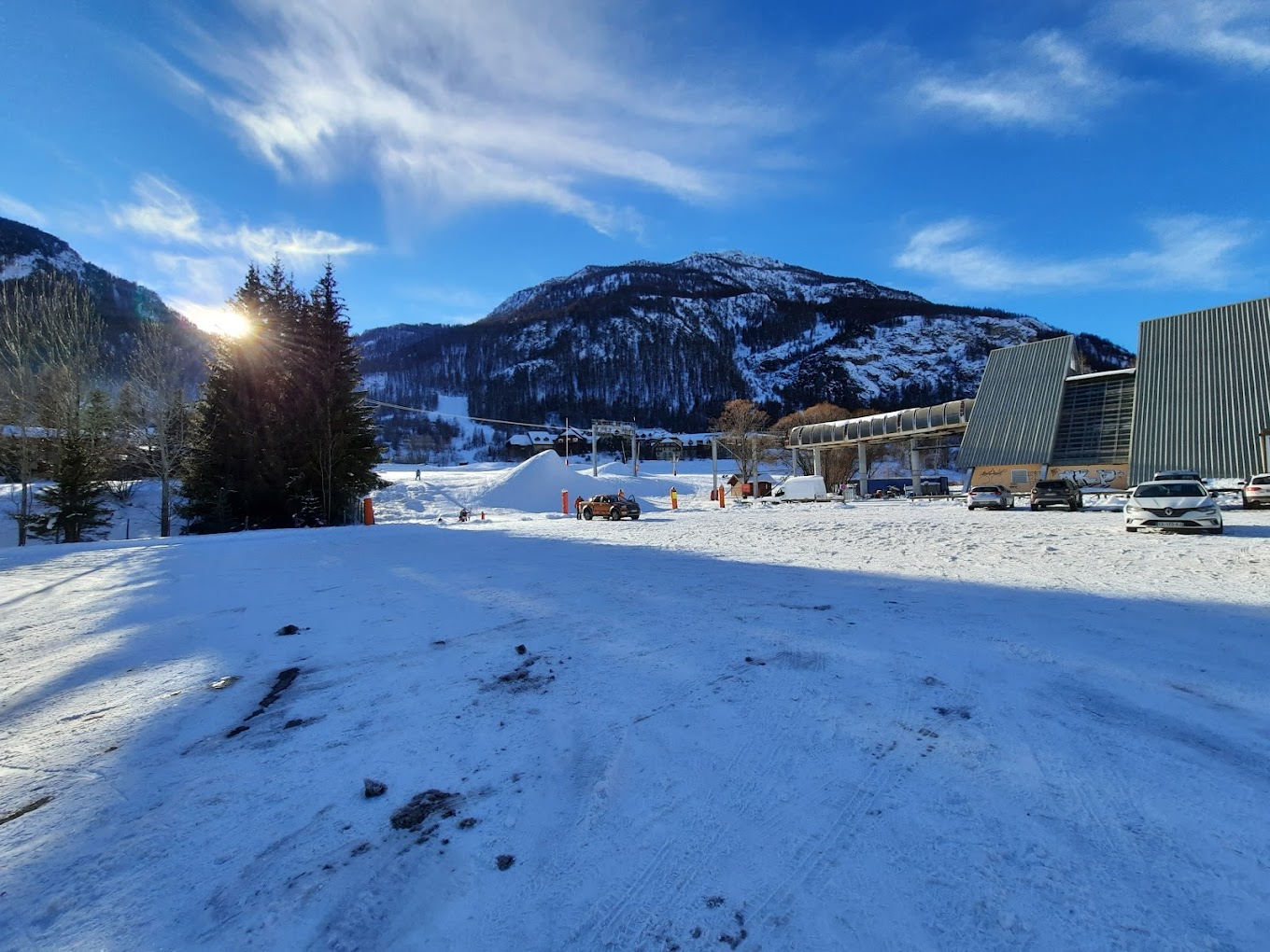 Villeneuve (Serre Chevalier) in France - a snow covered parking area with a mountain in the background.