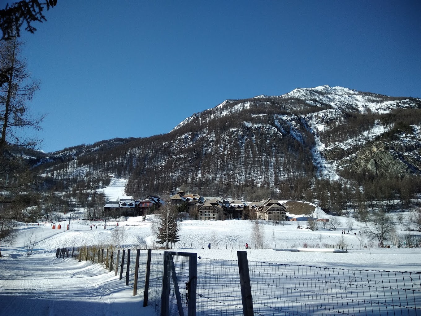 Villeneuve (Serre Chevalier) in France - a snow covered mountain with a fence in front of it.