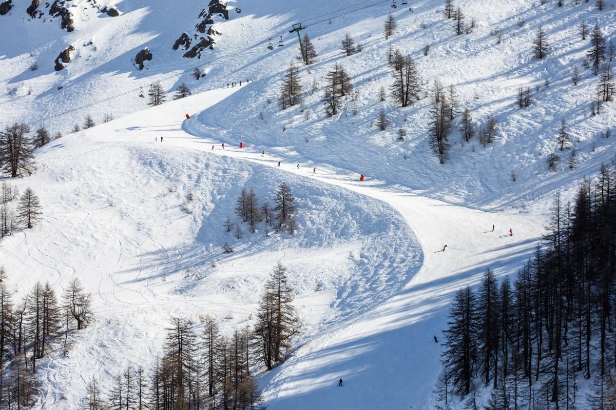 Villeneuve (Serre Chevalier) in France - a group of people skiing down a snowy slope.