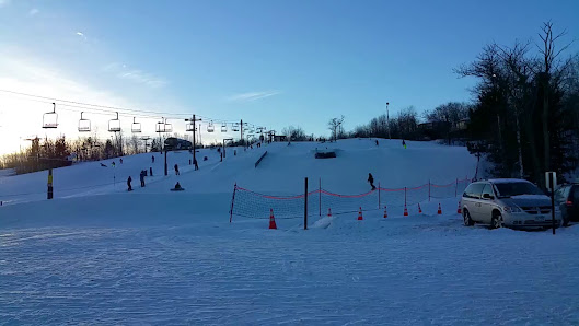 Winter sports scene at Spirit Mountain in Duluth, Minnesota, showing a skier and a group of people taking part in various ski activities against the backdrop of a bustling ski resort.