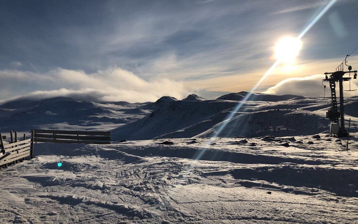 Uvdal Alpinsenter in Norway - the sun is shining over a snowy mountain.