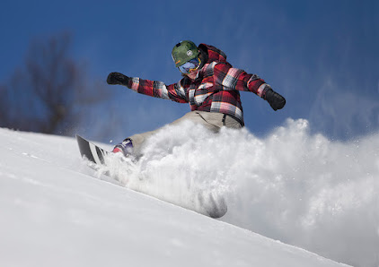 A snowboarder carving a path down the snow-covered slopes of Wintergreen Resort in Nellysford, Virginia. The crisp winter air is clear, highlighting the pristine beauty of the natural landscape.
