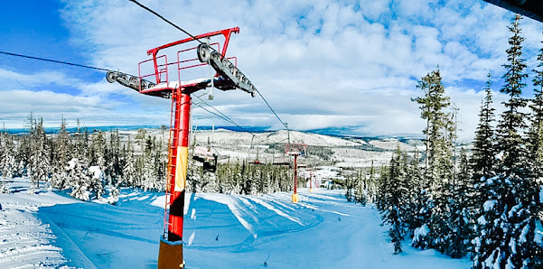 Ski lift ascending at Mount Timothy, Canadian ski resort. Winter sports enthusiasts frequent snow-covered slopes, with an active skier in sight.