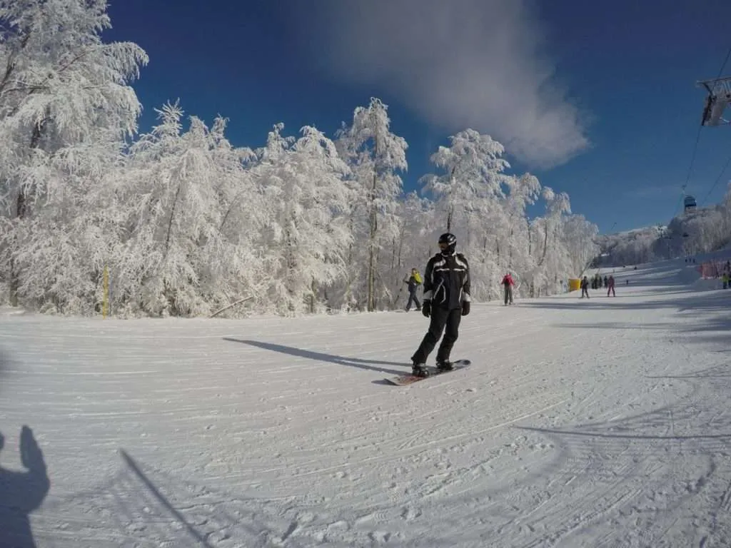 Stara Planina in Serbia - a person riding a snowboard down a snow covered slope.