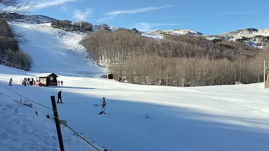 Winter scene at Corno alle Scale in Italy, featuring a skier enjoying the slopes of the ski resort, with ski lifts in the background adding to the vibrant winter sports atmosphere.