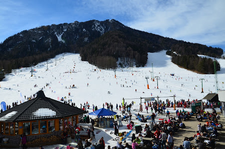 Winter afternoon at Kranjska Gora ski resort in Slovenia, featuring winter sports activities, a ski center, and a chalet amid enchanting snowy scenery.