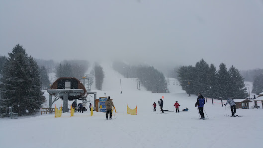 Winter sports enthusiasts enjoy the slopes at Greek Peak Mountain ski resort in Cortland, New York, USA. The scene features a ski lift, a cozy chalet, and stunning winter scenery.
