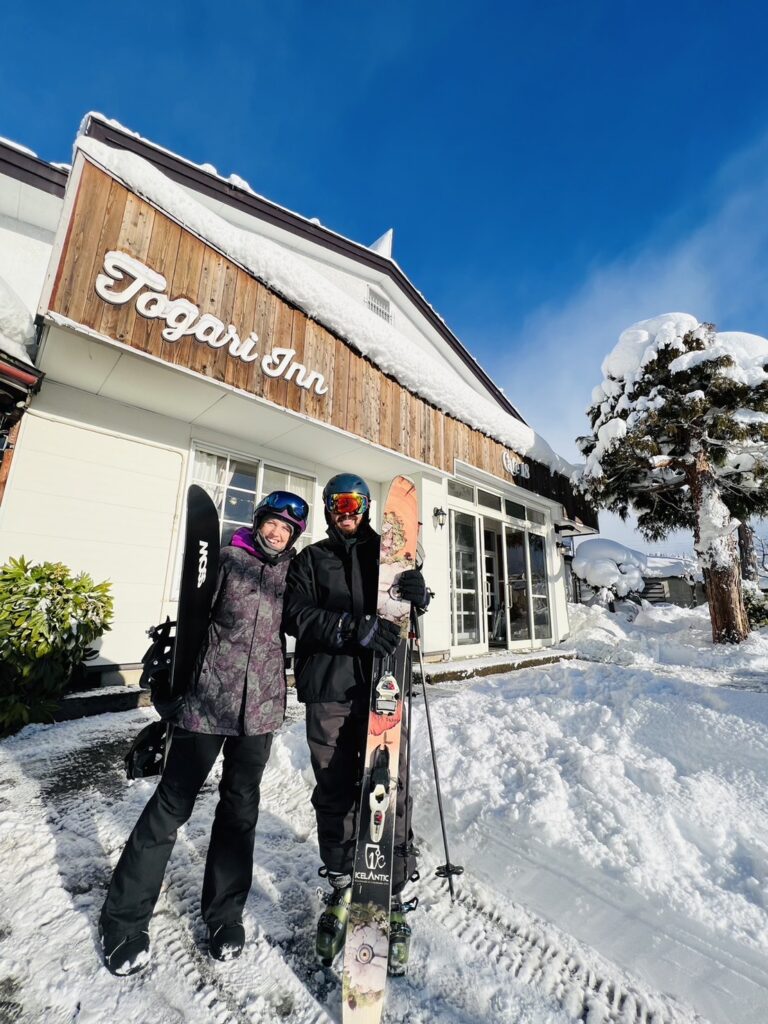 Togari Onsen in Japan: two people standing in the snow outside of a building.