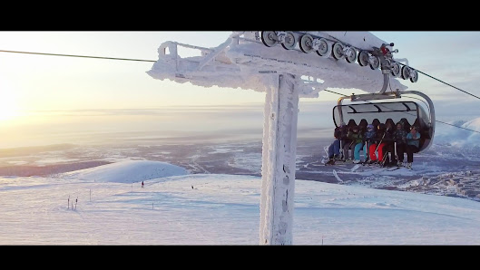 A ski lift amidst a stunning winter landscape at Kolasportland ski resort in Russia with skiers enjoying their winter sports in the background.