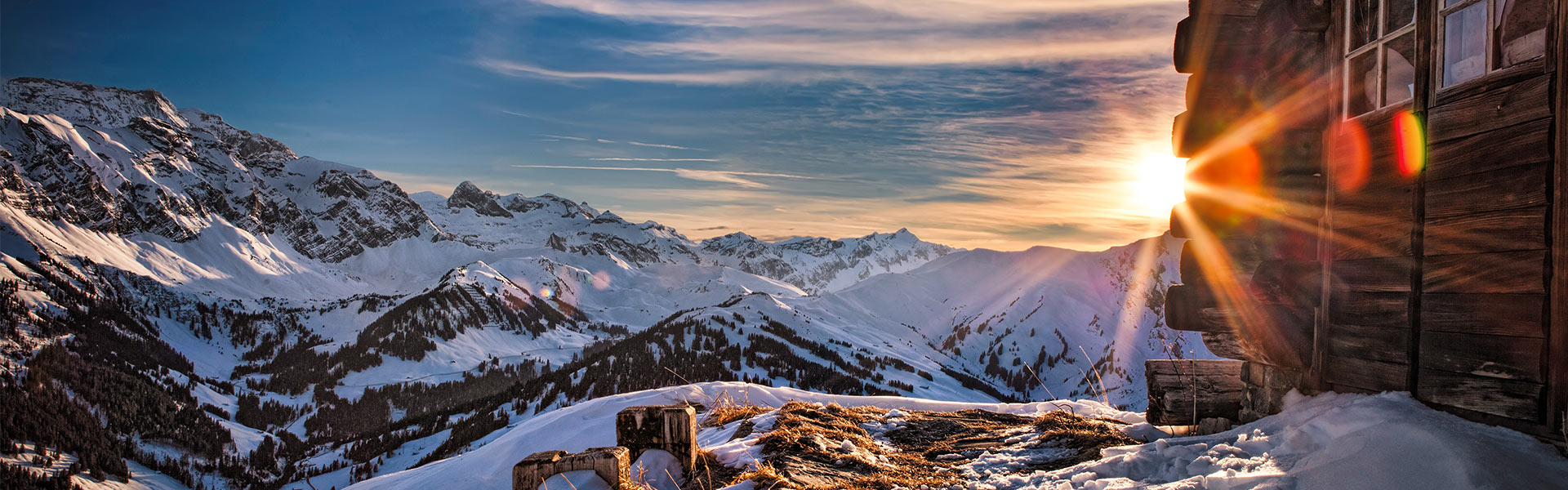 Tschentenalp in Switzerland - the sun is shining over a snowy mountain range.