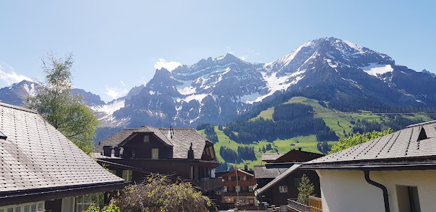 View of Tschentenalp in Adelboden Switzerland featuring a mountain a chalet and a ski resort on a sunny day. A mountain hut also adds to the scenic beauty.