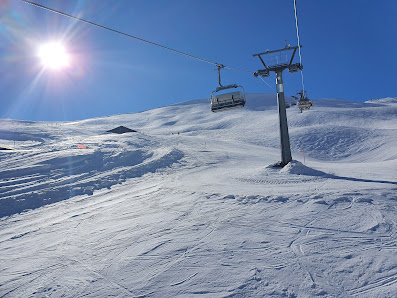 A ski resort in Tschentenalp Switzerland featuring a ski lift with a skier on the slope and a chalet nestled among snowy hills embodying a picturesque winter sports scene.