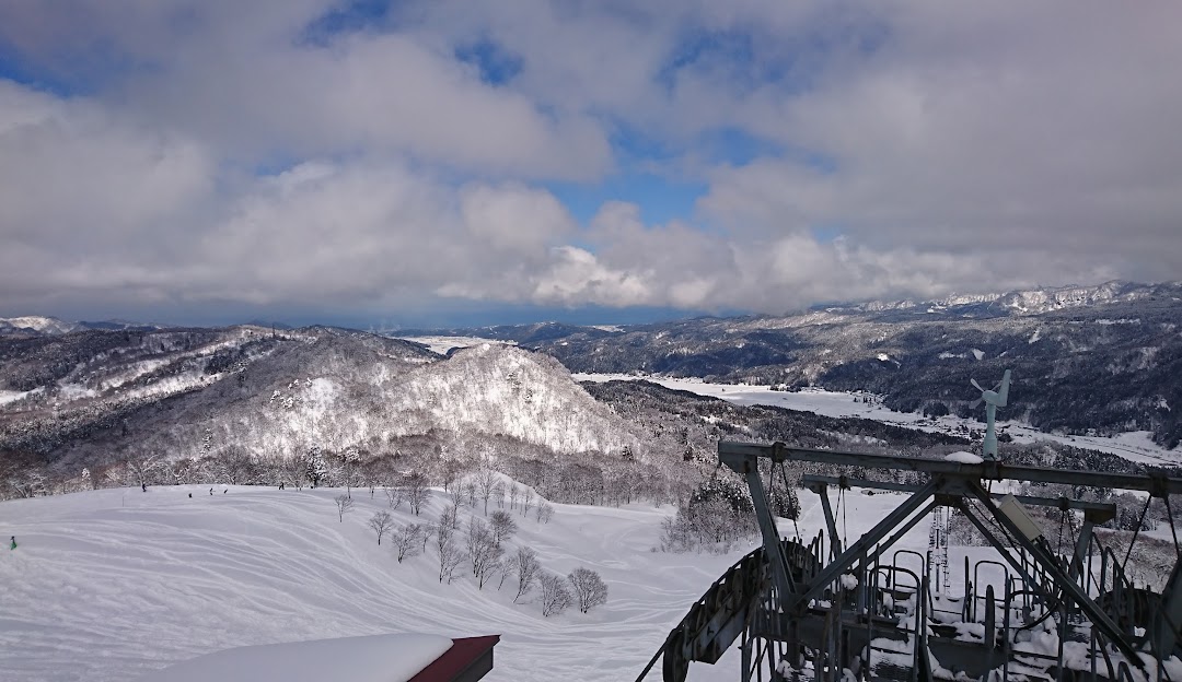 View of Itoigawa Seaside Valley in Japan featuring a bustling ski resort with a prominent ski lift, surrounded by pristine winter scenery. An alpine chalet adds to the picturesque setting.
