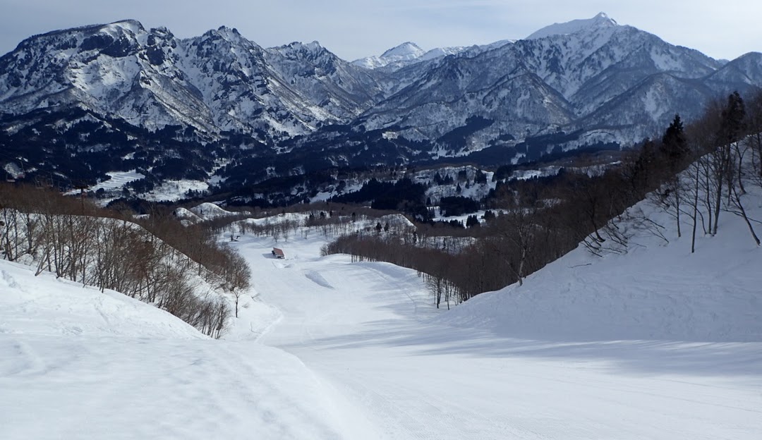 Winter scene at Itoigawa Seaside Valley, Japan. Snow covers the sprawling hills, dotted with ski resorts and chalets, emphasizing the area's popularity for winter sports.