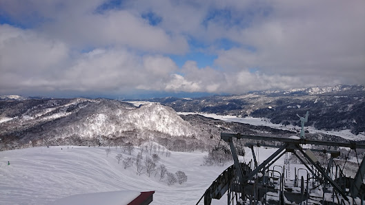 An captivating winter scene at Itoigawa Seaside Valley ski resort in Japan, with a ski lift zigzagging up the snow-covered mountain, complemented by quaint chalets nestled amidst this pristine setting.