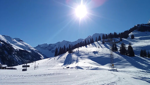 Sunny day at Wiriehornbahnen ski resort in Bernese Oberland, Switzerland. The scene captures the winter sports activities, with a skier on the slope and a charming chalet nearby.