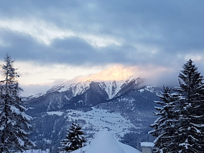 Stunning winter view of Skilifte und Sesselbahn Sarn Heinzenberg ski resort in Graubünden, Switzerland featuring a snow-covered mountain, ski facilities and athletes engaging in winter sports activities.