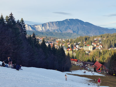 A bustling winter sports scene at Clăbucet ski resort in Predeal Romania. Skiers and snowboarders enjoy the snowy slopes amidst beautiful winter scenery with a charming chalet nestled nearby.