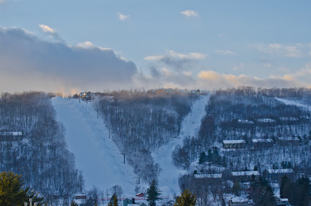 View of the stunning Wisp Resort in McHenry, Maryland, showcasing its snow-covered slopes. The scene includes skiers enjoying winter sports and a ski lift in operation.