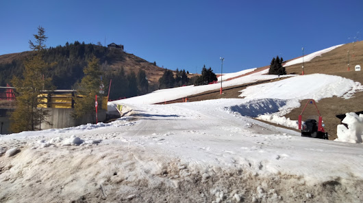 Image showcasing Bielmonte neve Lo Sci Per Tutti, a bustling ski resort in Piedmont, Biella, Italy. Multiple skiers dot the frosty landscape; a cozy chalet looms in the background.