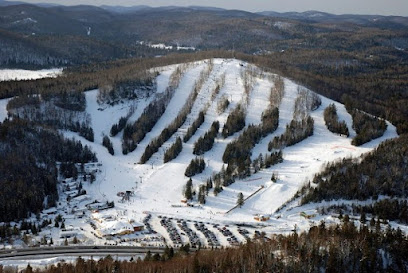 Wintertime at Belle Neige ski resort in Quebec, Canada, featuring snow-covered slopes and a ski lift, busy with winter sports enthusiasts.