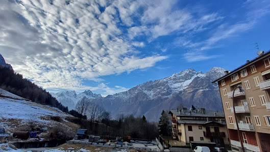 Chalet nestled amidst breathtaking winter scenery in Nuova Lizzola, Lombardy, featuring towering mountains and a lively winter sports scene.